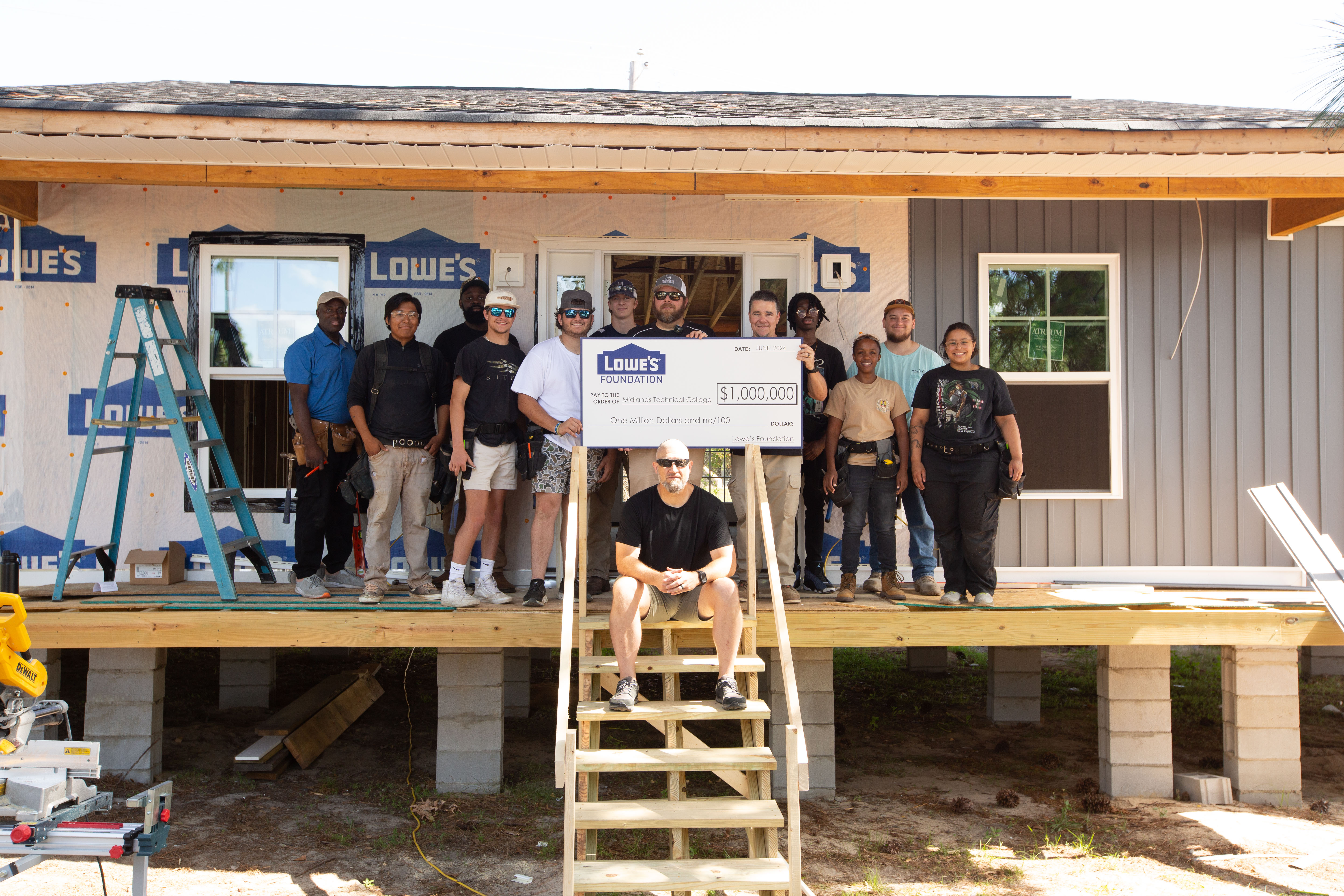 MTC students and faculty pose with a $1 million Gable Grant check from the Lowe's Foundation on the mock house on MTC's Airport Campus.