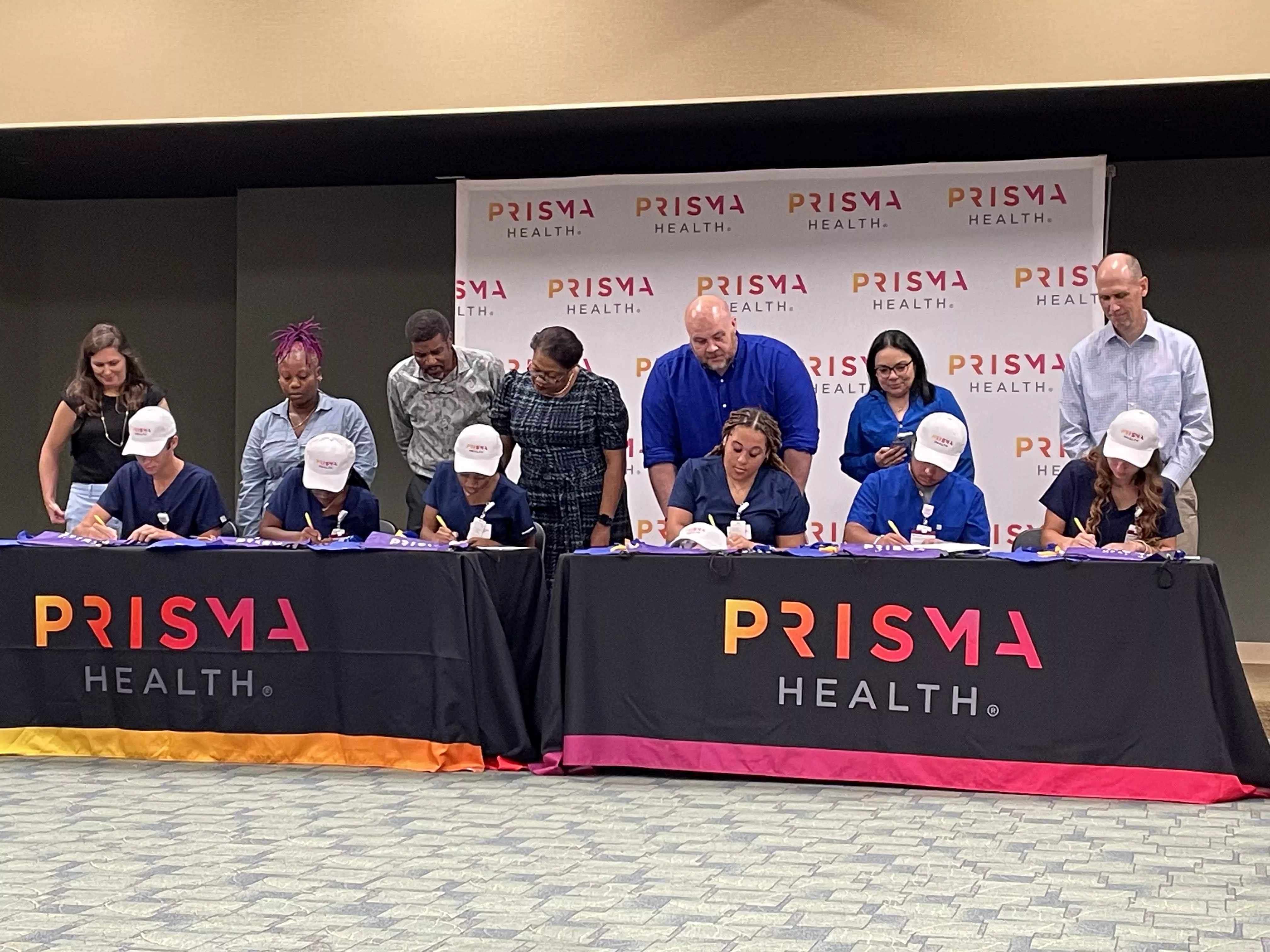 Image of six apprentices signing their agreement with Prisma Health